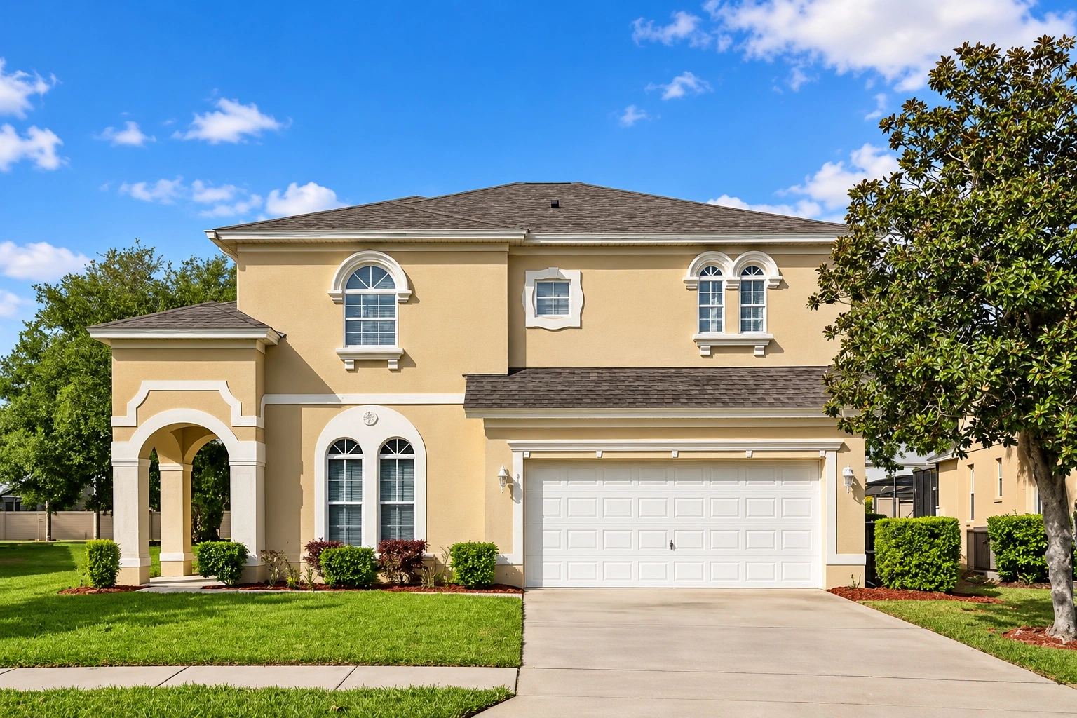 The warm cream exterior of Woosah Villa, with its front garden and driveway